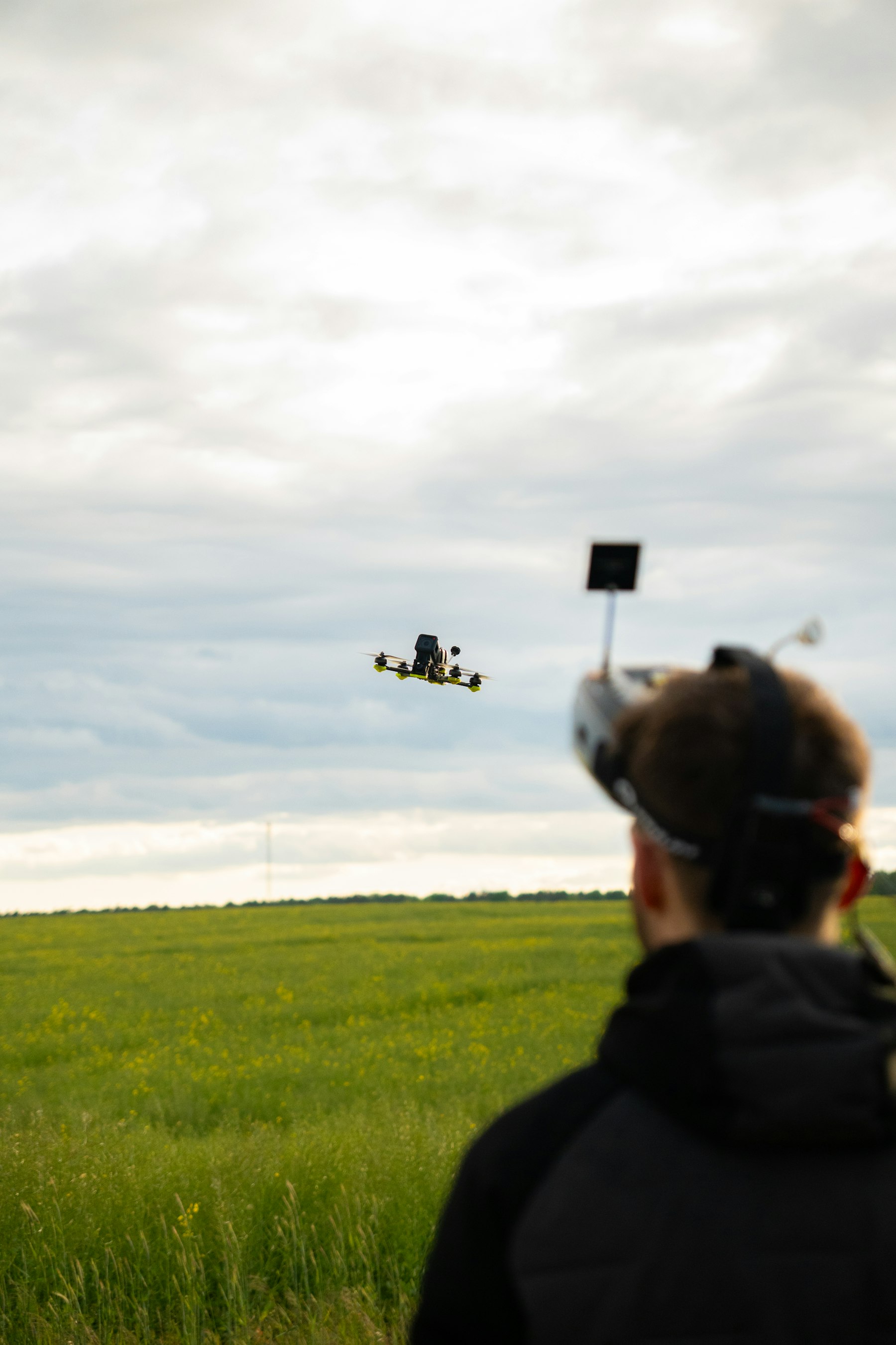 Pilot FPV w goglach steruje dronem wyścigowym nad zieloną łąką